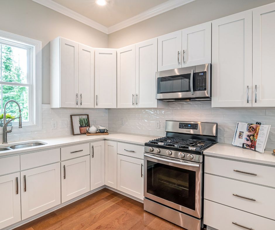 Painter applying fresh paint to kitchen cabinets during a renovation.